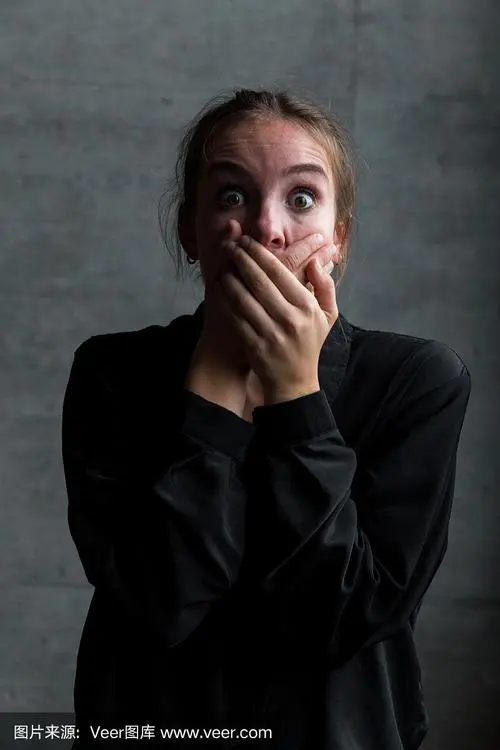 年轻的白人妇女与手在嘴和恐惧的面部表情
